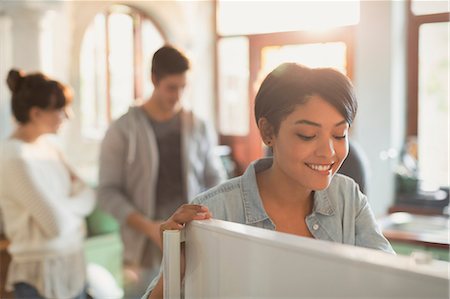 Smiling young woman looking into refrigerator in kitchen Stock Photo - Premium Royalty-Free, Code: 6124-08821067