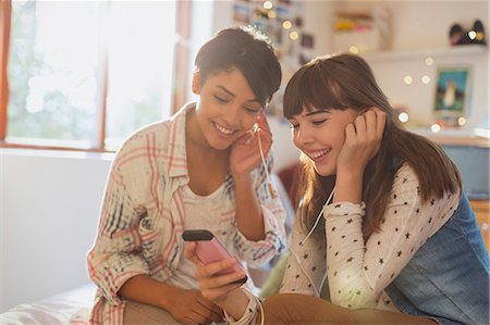 simsearch:6113-07906468,k - Young women friends sharing headphones listening to music with mp3 player Stock Photo - Premium Royalty-Free, Code: 6124-08821091