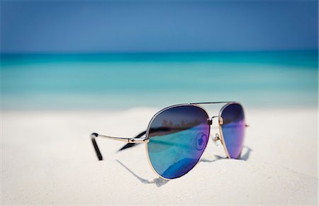 Close up aviator sunglasses in sand on sunny tropical ocean beach Stock Photo - Premium Royalty-Free, Code: 6124-08945966