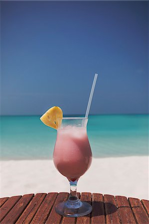 simsearch:632-06118390,k - Pink cocktail with pineapple slice and straw on sunny tropical ocean beach Stock Photo - Premium Royalty-Free, Code: 6124-08945985