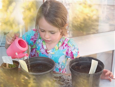 simsearch:649-05801120,k - Girl watering seedlings in flowerpots with tiny pink watering can Photographie de stock - Premium Libres de Droits, Code: 6124-08945902