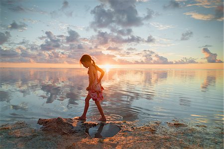 Girl wading in ocean surf on tranquil sunset beach Stock Photo - Premium Royalty-Free, Code: 6124-08945927