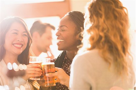 simsearch:649-07063514,k - Smiling women friends toasting beer glasses in bar Stock Photo - Premium Royalty-Free, Code: 6124-08946042