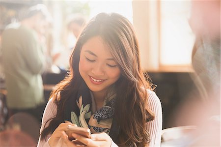 schnurloses telefon - Smiling Chinese woman texting with cell phone in cafe Stockbilder - Premium RF Lizenzfrei, Bildnummer: 6124-08946049