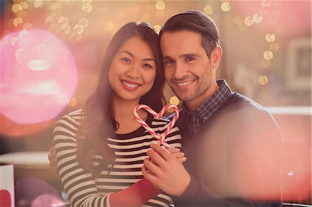 simsearch:6124-08946032,k - Portrait smiling couple holding heart-shape candy canes Fotografie stock - Premium Royalty-Free, Codice: 6124-08946016