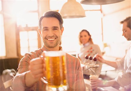 Portrait smiling man toasting beer stein in bar Stock Photo - Premium Royalty-Free, Code: 6124-08946109