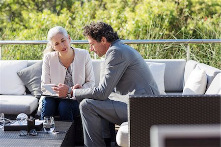 Businessman and businesswoman using digital tablet on balcony patio sofa Stock Photo - Premium Royalty-Free, Code: 6124-08907884