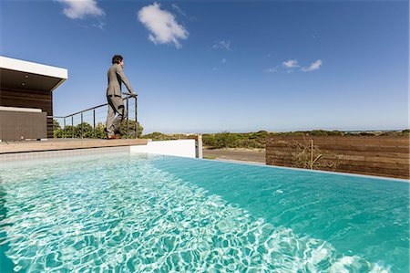 simsearch:6124-08907874,k - Businessman standing on luxury sunny patio with infinity pool, looking at view Stock Photo - Premium Royalty-Free, Code: 6124-08907944
