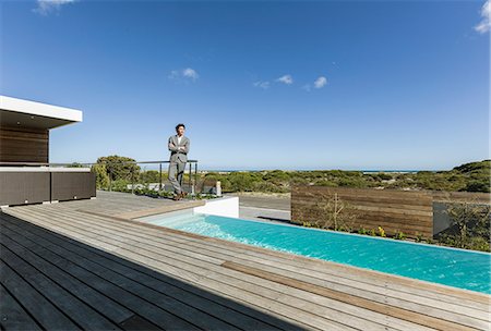 simsearch:6124-08907966,k - Businessman on sunny modern, luxury patio with infinity pool Stock Photo - Premium Royalty-Free, Code: 6124-08907951