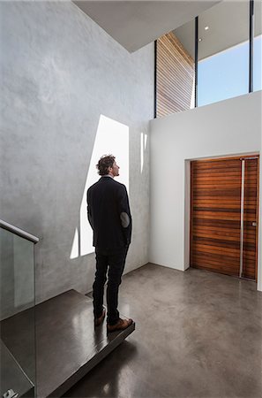 rear view man hands in pocket - Pensive businessman standing in modern home showcase interior foyer Foto de stock - Sin royalties Premium, Código: 6124-08907910