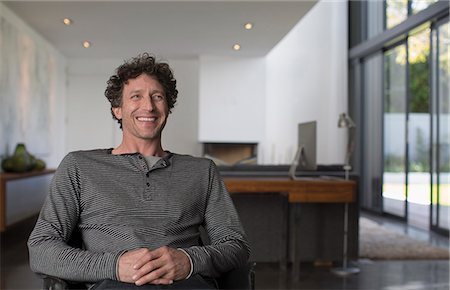 Happy man looking away in living room Stock Photo - Premium Royalty-Free, Code: 6124-08907924