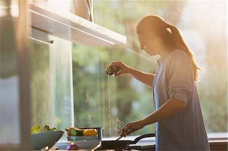 simsearch:6113-09059257,k - Woman pouring oil into pan on stove in kitchen Photographie de stock - Premium Libres de Droits, Code: 6124-08908045