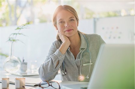 simsearch:6113-09111906,k - Portrait confident female doctor working at laptop in doctor’s office Foto de stock - Sin royalties Premium, Código: 6124-08908046