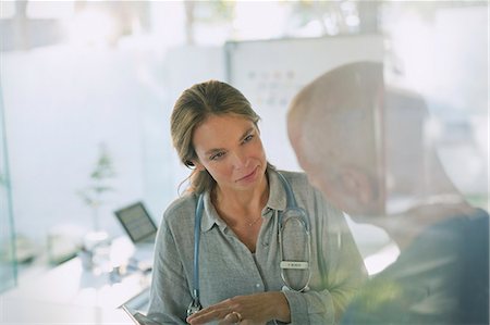 Serious female doctor with digital tablet talking to male patient in doctor’s office Stock Photo - Premium Royalty-Free, Code: 6124-08908072