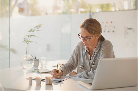 simsearch:6124-08908087,k - Female doctor writing prescriptions at desk in doctor’s office Fotografie stock - Premium Royalty-Free, Codice: 6124-08908141