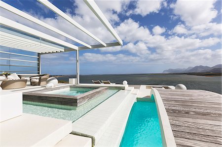 simsearch:6113-07565205,k - Sunny, tranquil modern luxury patio with swimming pool and footbridge with ocean view Foto de stock - Sin royalties Premium, Código: 6124-08908199