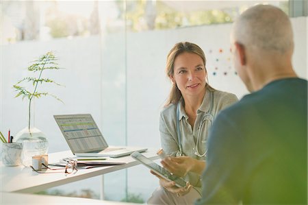 Female doctor showing digital tablet to male patient in doctor’s office Photographie de stock - Premium Libres de Droits, Code: 6124-08908105