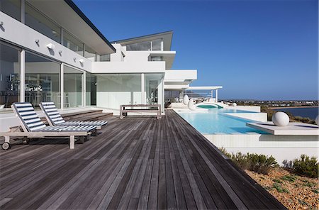 simsearch:6124-08908186,k - Sunny modern luxury home showcase exterior patio with infinity pool Foto de stock - Sin royalties Premium, Código: 6124-08908200