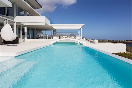 simsearch:6124-08908187,k - Sunny, tranquil modern luxury home showcase exterior swimming pool and patio Stock Photo - Premium Royalty-Free, Code: 6124-08908218