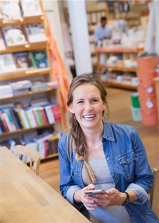 Portrait laughing pregnant woman using cell phone in shop Stock Photo - Premium Royalty-Free, Code: 6124-08926873