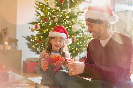 simsearch:6124-08926935,k - Father and daughter wearing Santa hats and holding paper snowflakes near Christmas tree Stock Photo - Premium Royalty-Free, Code: 6124-08926895