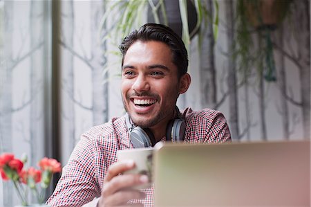 simsearch:6113-08321133,k - Man laughing and drinking coffee at laptop in cafe Stock Photo - Premium Royalty-Free, Code: 6124-08926813