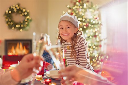 Portrait smiling girl wearing paper crown at Christmas dinner table Stock Photo - Premium Royalty-Free, Code: 6124-08926945