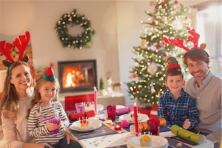 Portrait smiling young family wearing costume reindeer antlers at Christmas dinner table Stock Photo - Premium Royalty-Free, Code: 6124-08926949