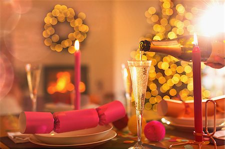 picture of champagne bottle and champagne flute - Pouring champagne into champagne flute on Christmas dinner table with Christmas cracker Stock Photo - Premium Royalty-Free, Code: 6124-08926954
