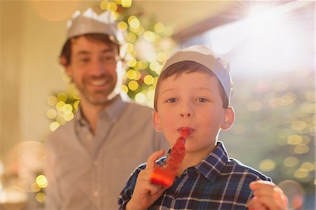 simsearch:6124-08926935,k - Portrait boy wearing Christmas paper crown blowing party favor Stock Photo - Premium Royalty-Free, Code: 6124-08926959