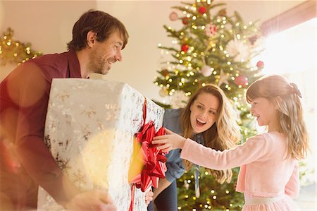 Parents giving large Christmas gift to daughter near Christmas tree Stock Photo - Premium Royalty-Free, Code: 6124-08926965