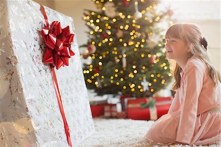 simsearch:614-06624568,k - Girl smiling in anticipation at large Christmas gift near Christmas tree Stock Photo - Premium Royalty-Free, Code: 6124-08926999