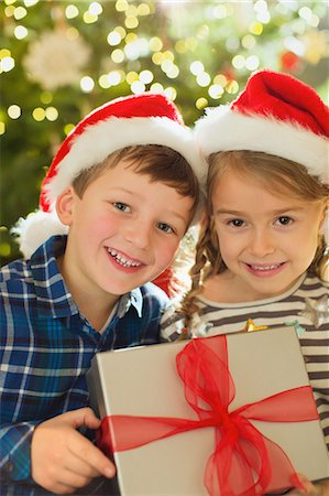 simsearch:632-06354048,k - Portrait smiling brother and sister in Santa hats holding Christmas gift Foto de stock - Sin royalties Premium, Código: 6124-08926904