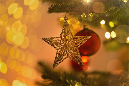 simsearch:632-06354271,k - Close up gold star ornament hanging from Christmas tree branch Photographie de stock - Premium Libres de Droits, Code: 6124-08926930