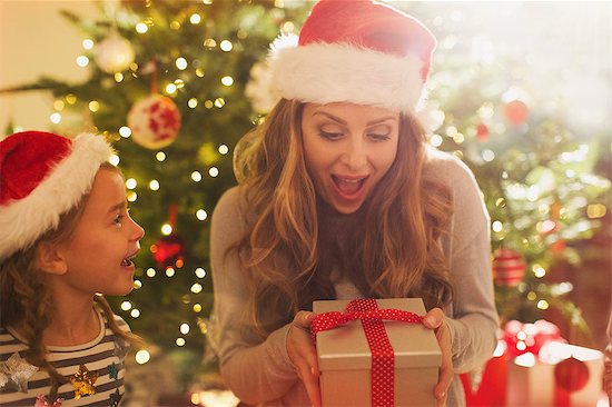 Surprised mother with Santa hat receiving Christmas gift from daughter Stock Photo - Premium Royalty-Free, Image code: 6124-08926936