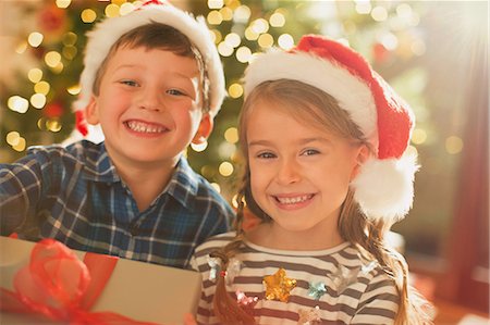 simsearch:632-06354048,k - Portrait smiling, enthusiastic brother and sister wearing Santa hats holding Christmas gift Foto de stock - Sin royalties Premium, Código: 6124-08926938