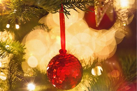 Close up red sequin ornament hanging from branch of Christmas tree with string lights Stockbilder - Premium RF Lizenzfrei, Bildnummer: 6124-08926939
