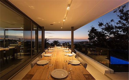 Illuminated wooden patio table with placesettings at dusk Stock Photo - Premium Royalty-Free, Code: 6124-08927052