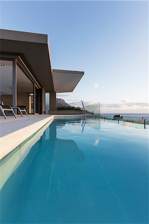 Tranquil blue lap swimming pool outside modern luxury home showcase exterior Foto de stock - Sin royalties Premium, Código: 6124-08927062