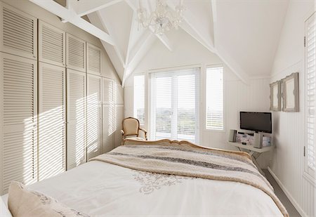 simsearch:6113-07731052,k - Tranquil sunny white bedroom with vaulted ceiling Fotografie stock - Premium Royalty-Free, Codice: 6124-08927097