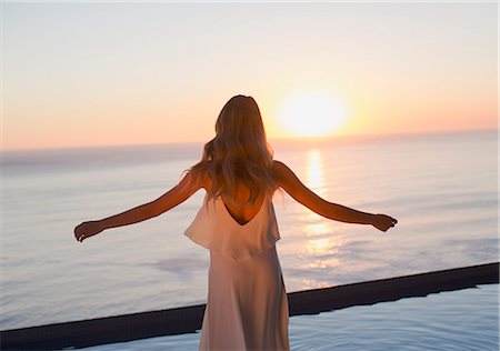 simsearch:6124-08743313,k - Woman with arms outstretched watching tranquil sunset view over ocean horizon Foto de stock - Sin royalties Premium, Código: 6124-09099742