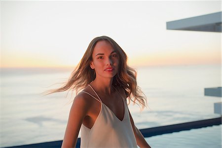 enjoying the view - Portrait confident woman turning on luxury balcony with sunset ocean view Stock Photo - Premium Royalty-Free, Code: 6124-09099762