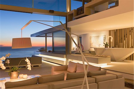 simsearch:6124-08908226,k - Illuminated, modern luxury home showcase interior living room with ocean view at dusk Photographie de stock - Premium Libres de Droits, Code: 6124-09099726