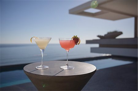 simsearch:6113-07147606,k - Cocktails in martini glasses on sunny luxury patio with sunny ocean view Photographie de stock - Premium Libres de Droits, Code: 6124-09099801