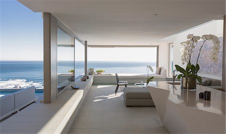 Modern, luxury home showcase interior living room with sunny ocean view Photographie de stock - Premium Libres de Droits, Code: 6124-09099832