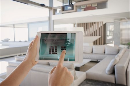 Personal perspective woman with digital tablet managing digital security system in modern, luxury home showcase interior living room Stock Photo - Premium Royalty-Free, Code: 6124-09099834