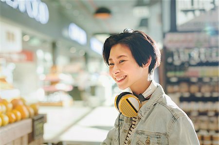 simsearch:6124-09004806,k - Smiling young woman with headphones grocery shopping in market Foto de stock - Sin royalties Premium, Código: 6124-09004797