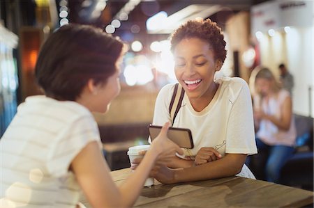 simsearch:6124-08170638,k - Young women friends using cell phone and drinking coffee in cafe Stock Photo - Premium Royalty-Free, Code: 6124-09004859