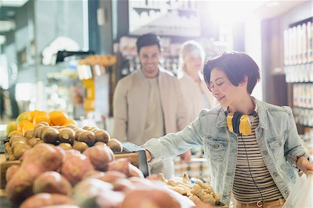 retail store - Young woman with headphones grocery shopping, browsing produce in market Stock Photo - Premium Royalty-Free, Code: 6124-09004864