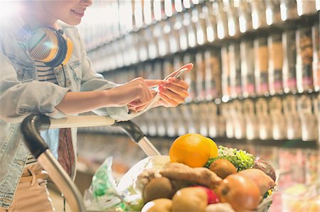 simsearch:6113-07791041,k - Young woman with headphones using cell phone, grocery shopping in market Stock Photo - Premium Royalty-Free, Code: 6124-09004876